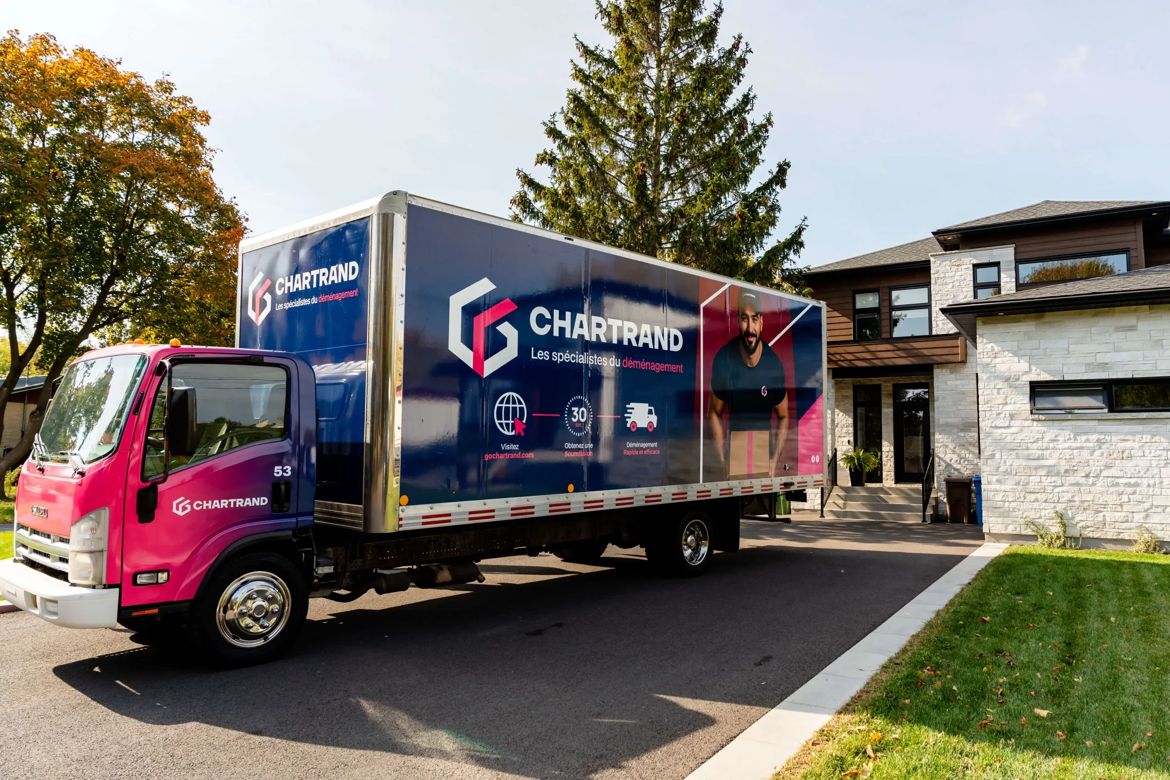 Camion Chartrand garé dans l’allée d’une maison moderne en pierre, vu de côté