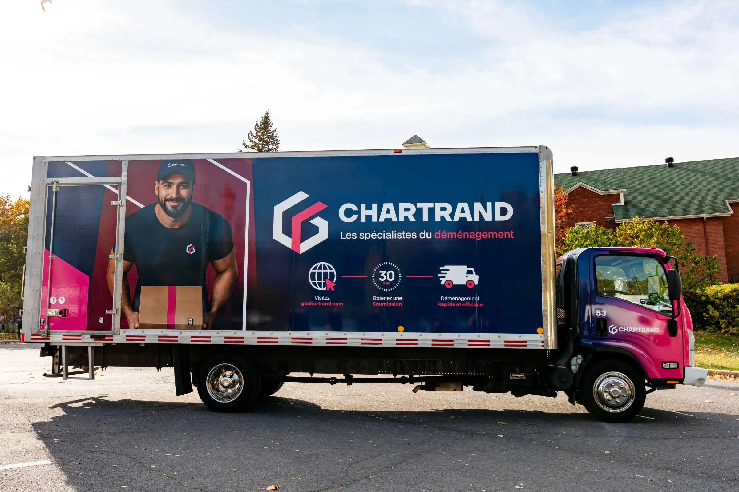 Camion Chartrand vu de côté devant des arbres aux couleurs d’automne
