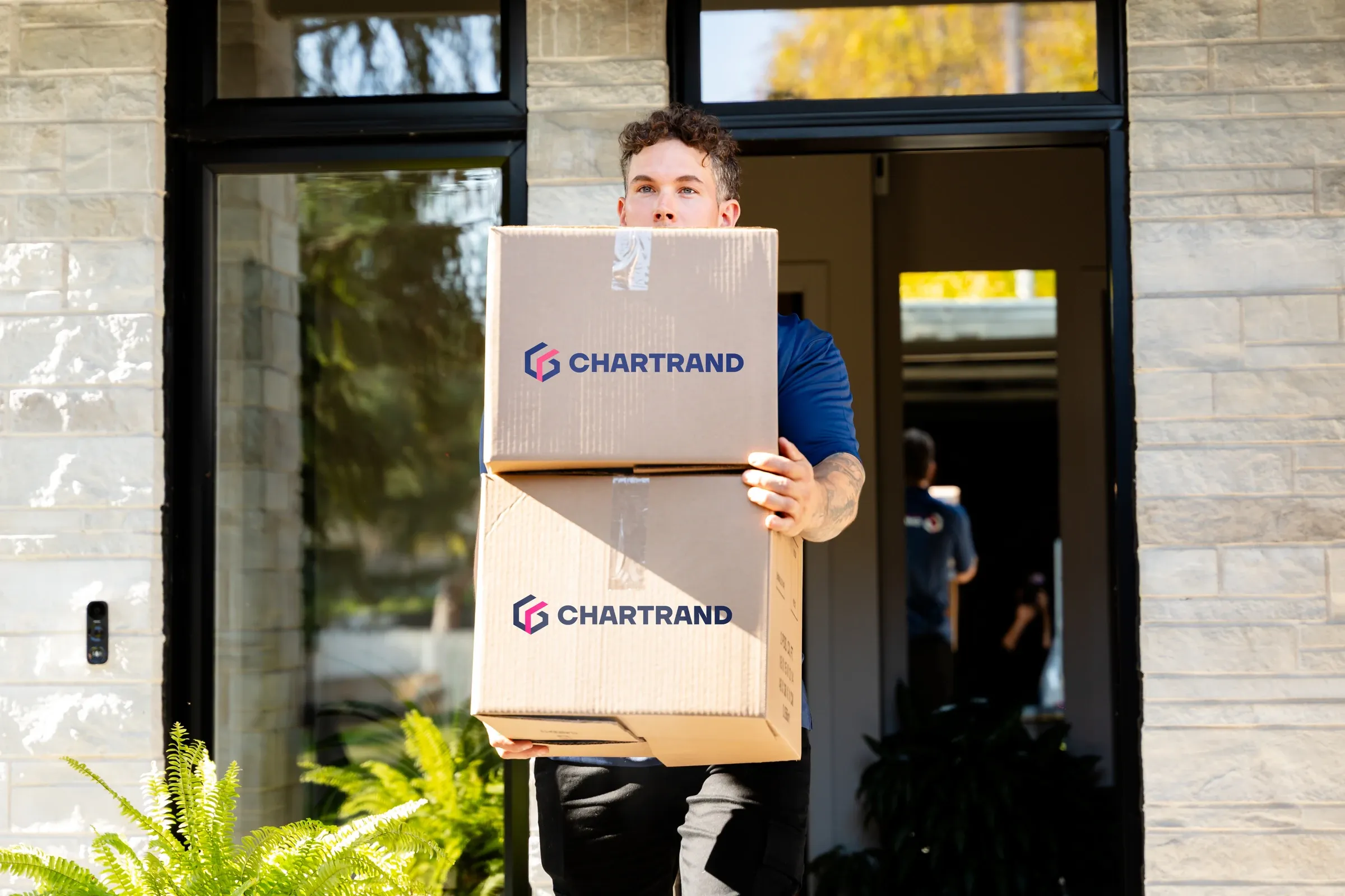 Déménageur Chartrand transportant deux boîtes à l’entrée d’une maison