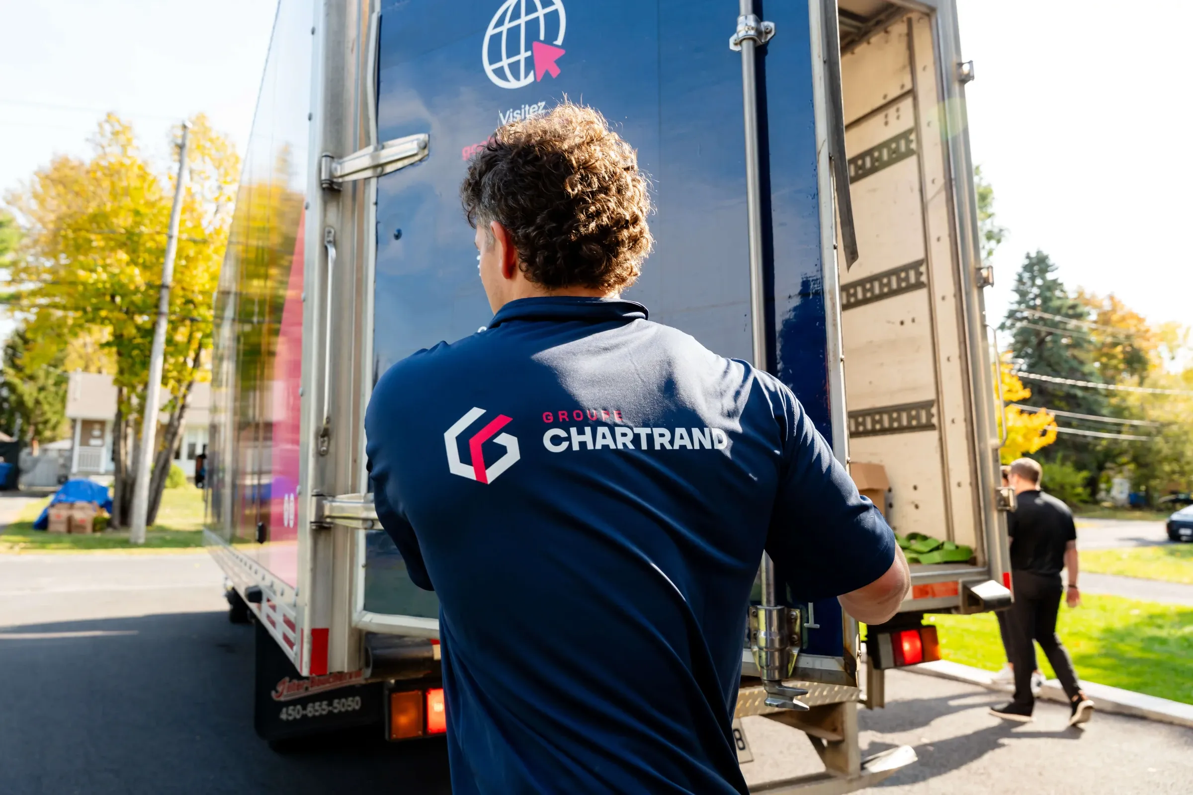Déménageur Chartrand de dos devant l’arrière ouvert d’un camion