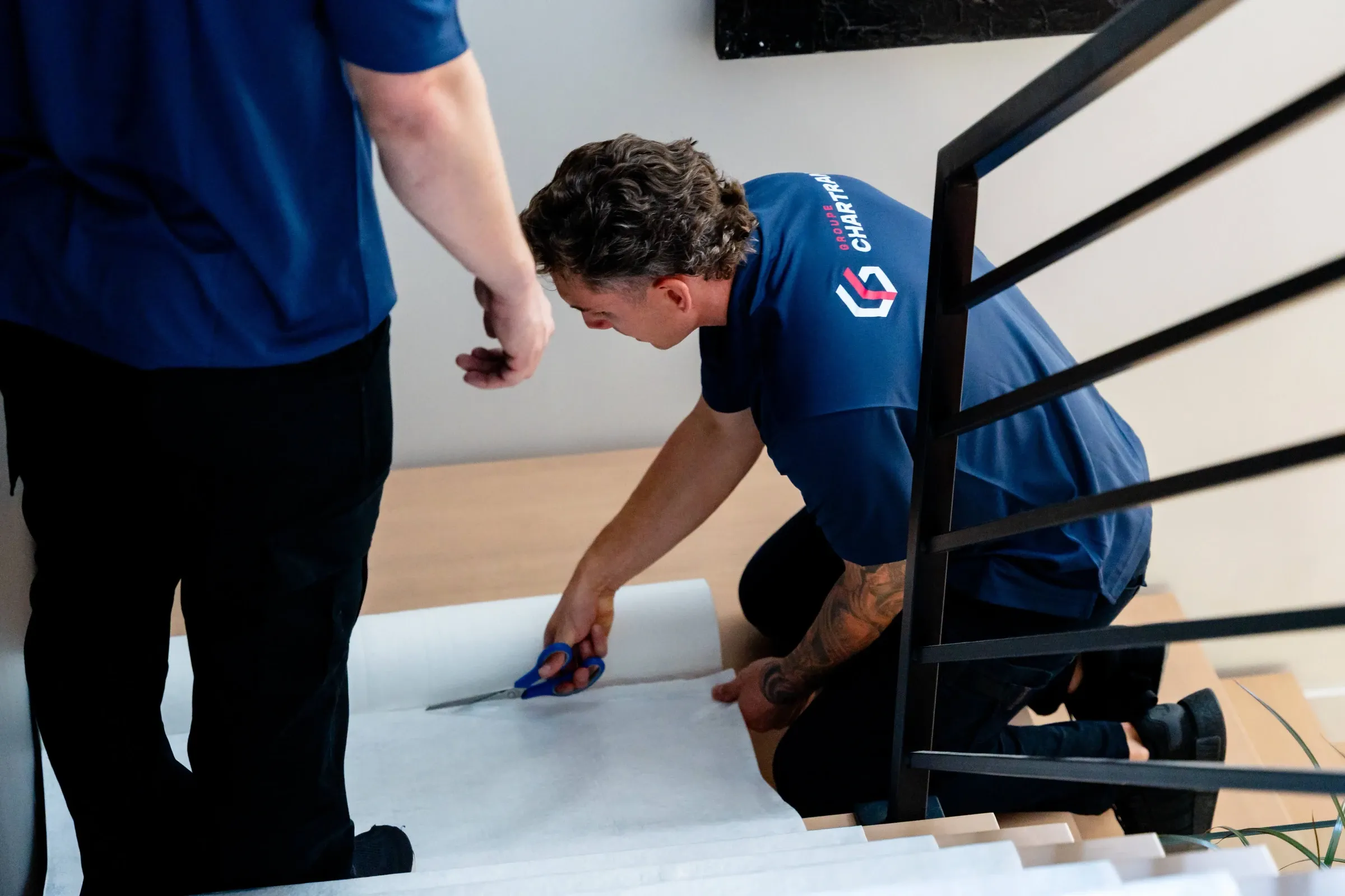 Déménageur Chartrand coupant un tapis de protection au pied d’un escalier