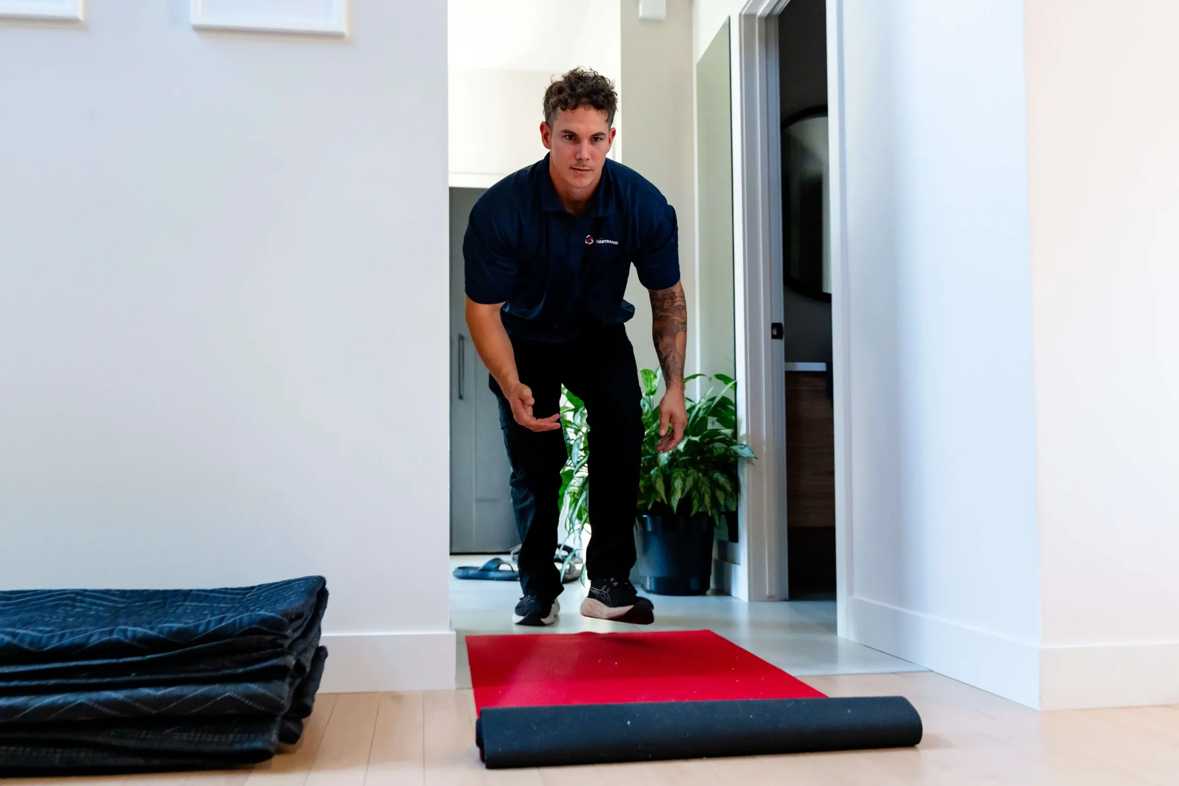 Déménageur Chartrand déroulant un tapis de protection sur le plancher d’une entrée