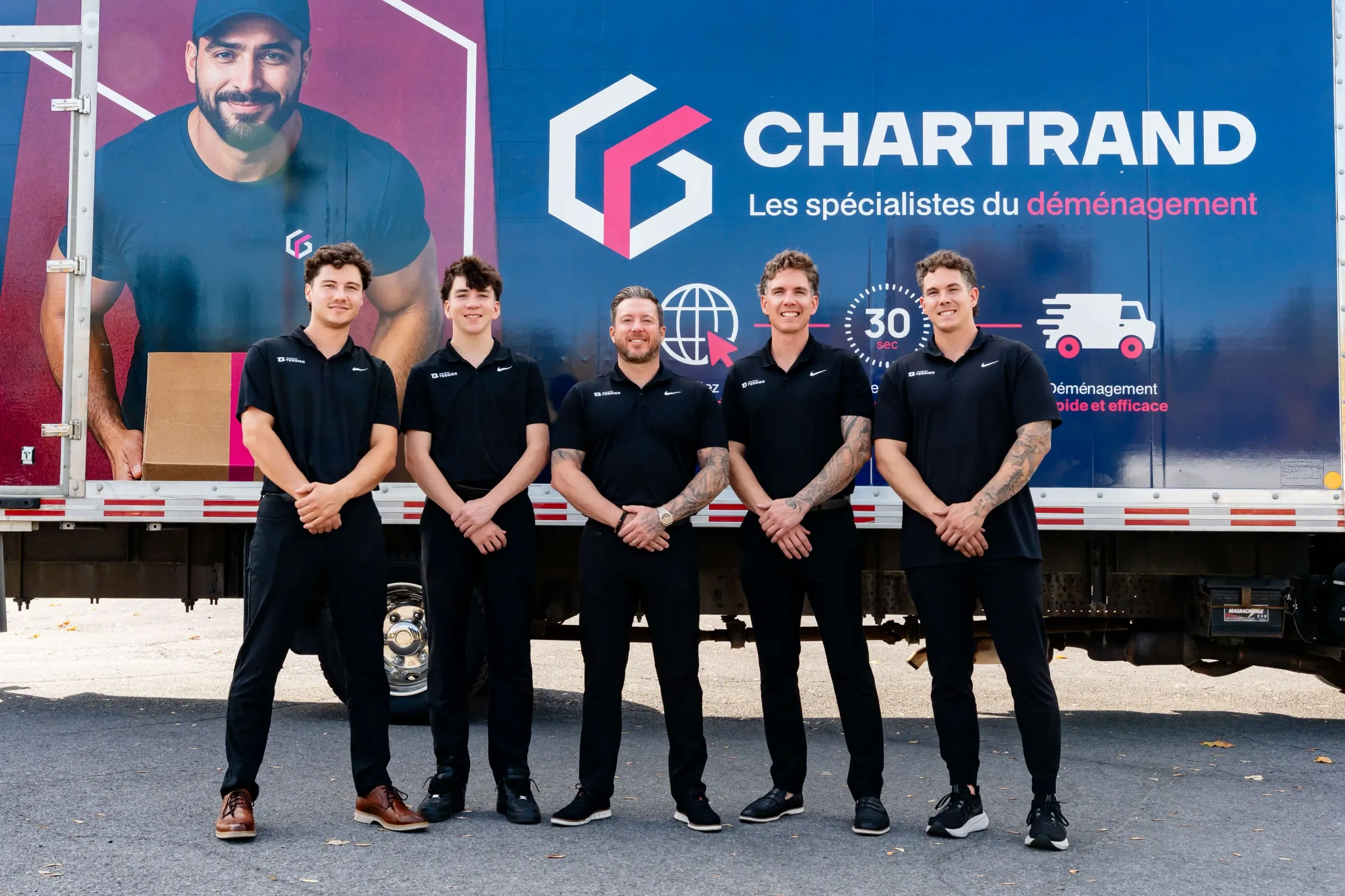 Cinq membres de l’équipe Chartrand debout devant le logo d’un camion Chartrand